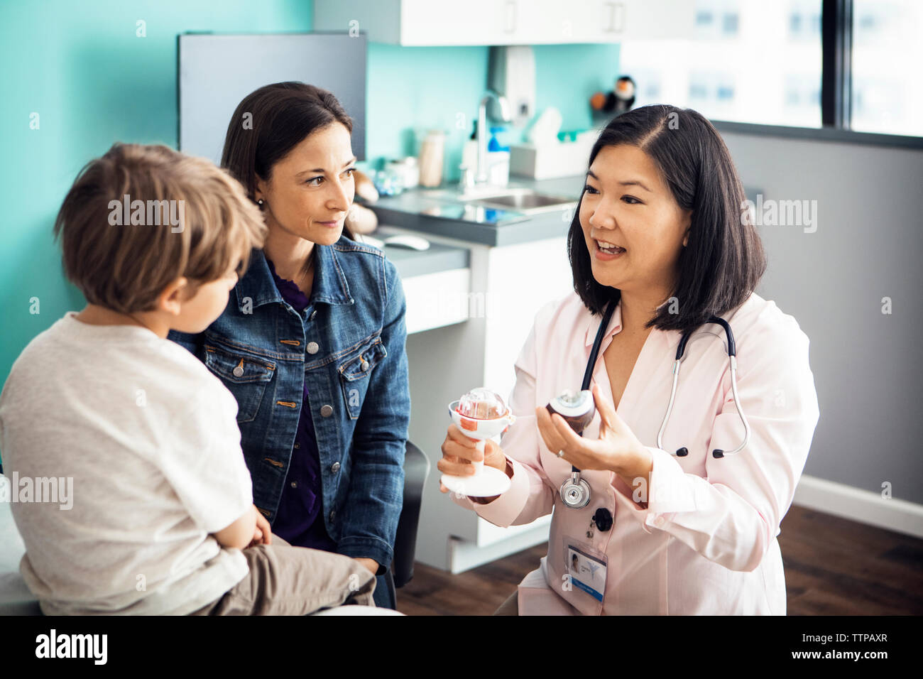 Female doctor explaining medical equipment to family in clinic Stock Photo