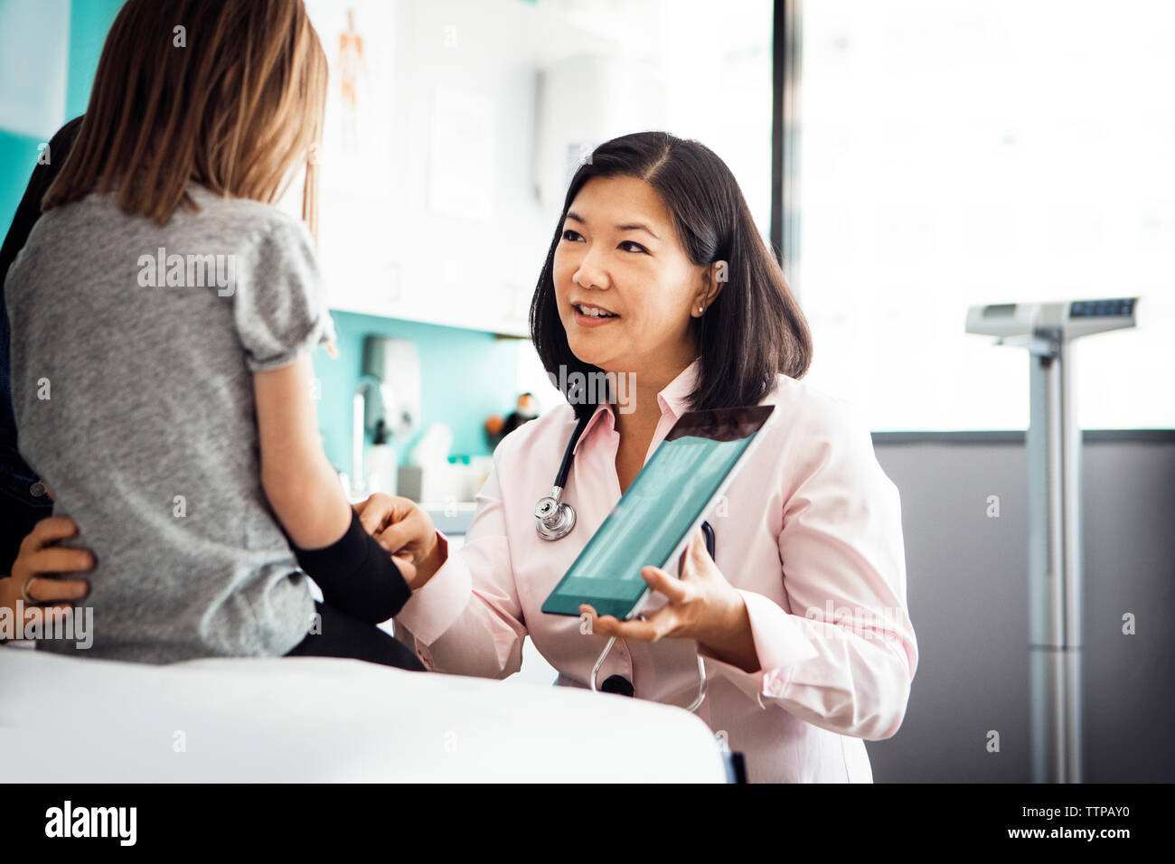 Female doctor showing hand x-ray on tablet computer to girl in clinic Stock Photo