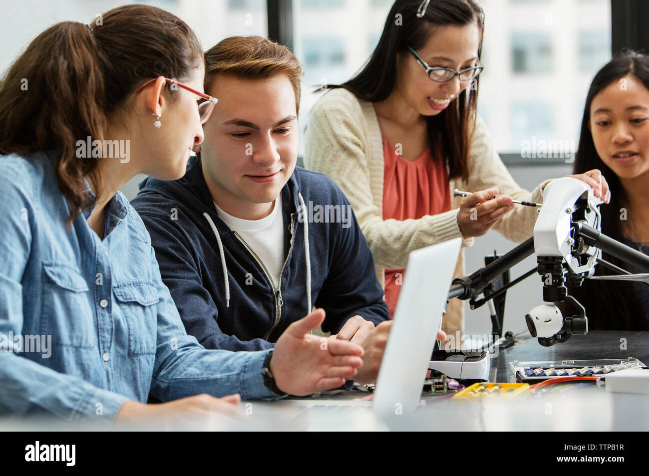 Teacher explaining drone while students discussing over laptop in classroom Stock Photo