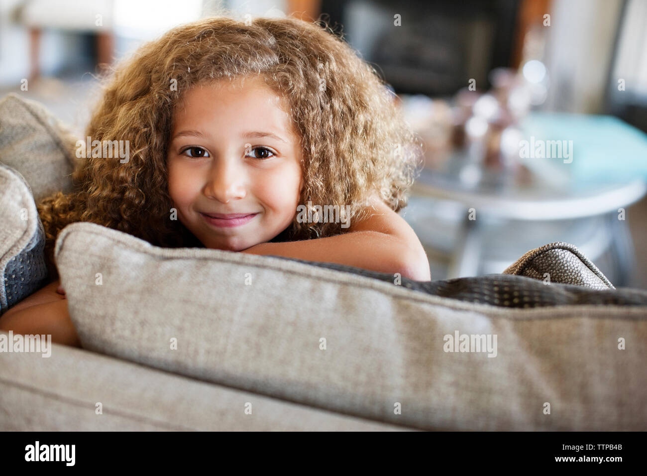 Portrait of happy girl sitting on sofa at home Stock Photo - Alamy
