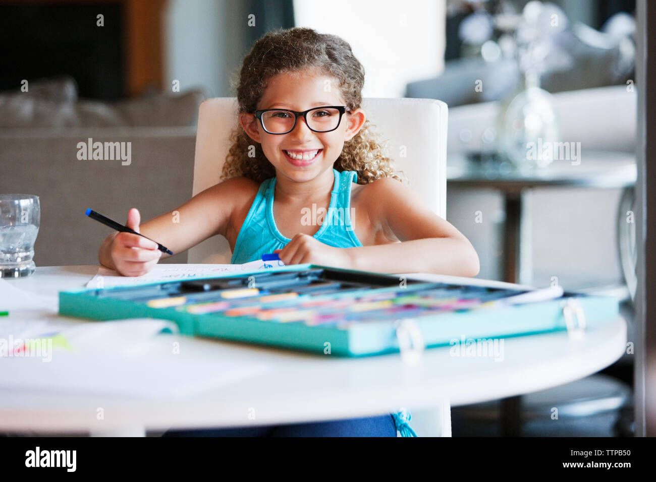Portrait of happy girl holding felt tip pen at table Stock Photo