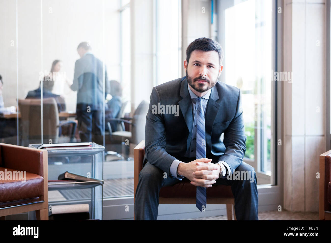 Portrait of businessman sitting with hands clasped in office Stock Photo