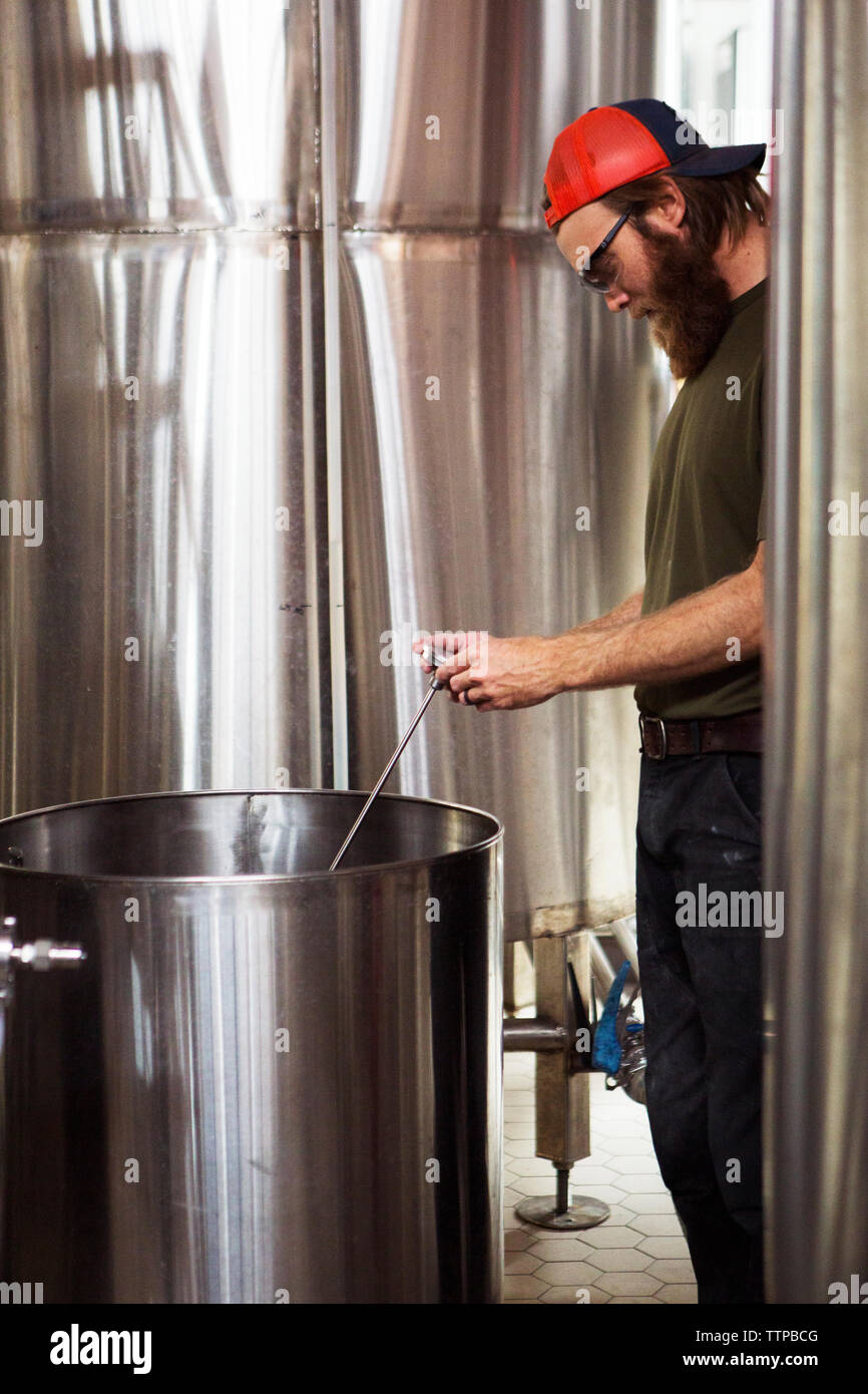 Brewer using thermometer while working at brewery Stock Photo