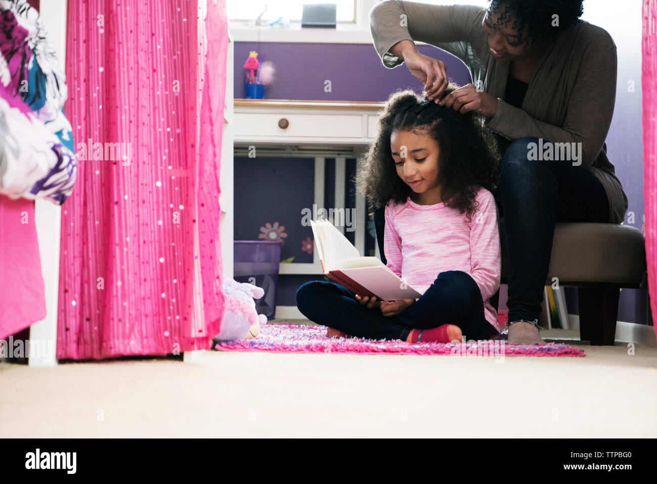 Woman combing daughter's hair at home Stock Photo