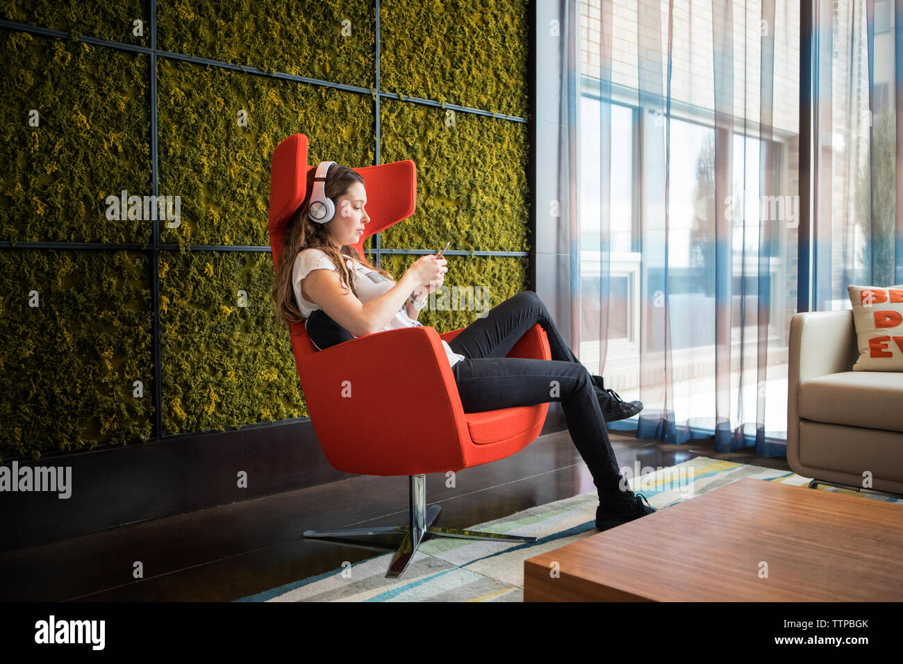 Side View Of Woman Listening Music While Sitting On Armchair At Home Stock Photo Alamy