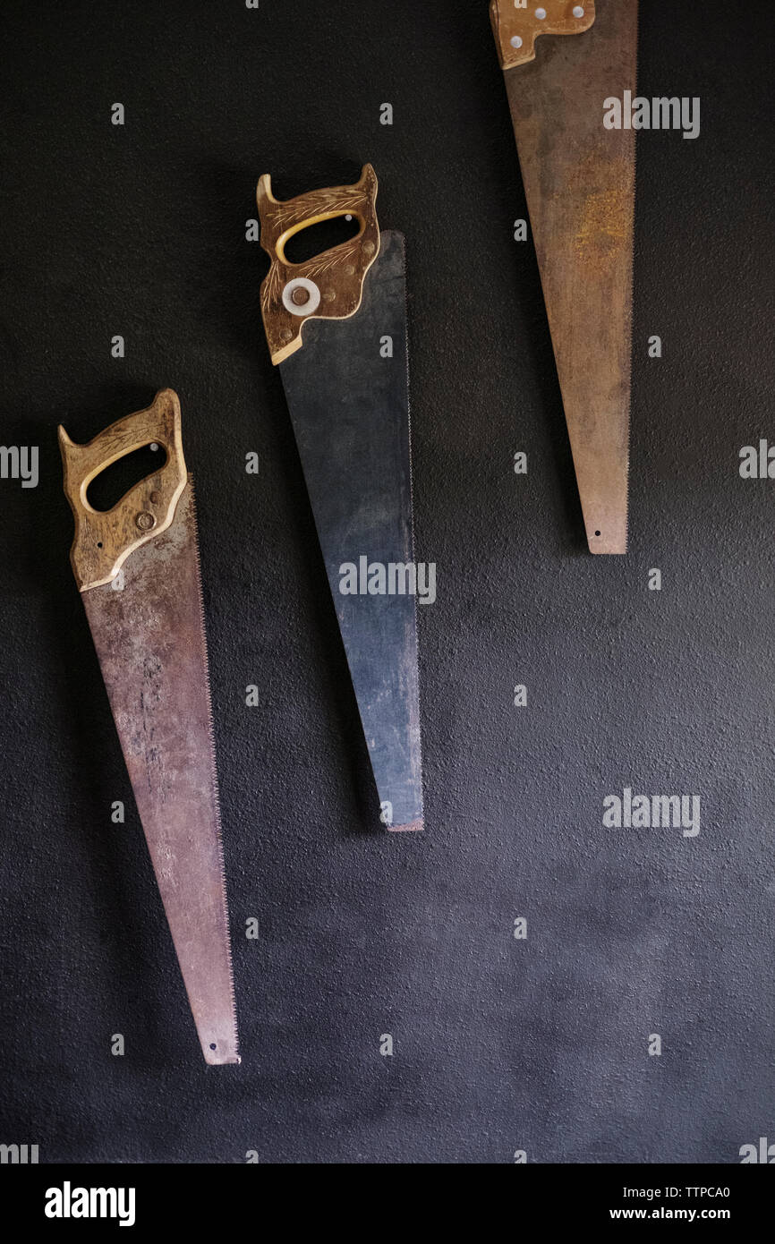 Old rusty hand saws hanging on wall Stock Photo