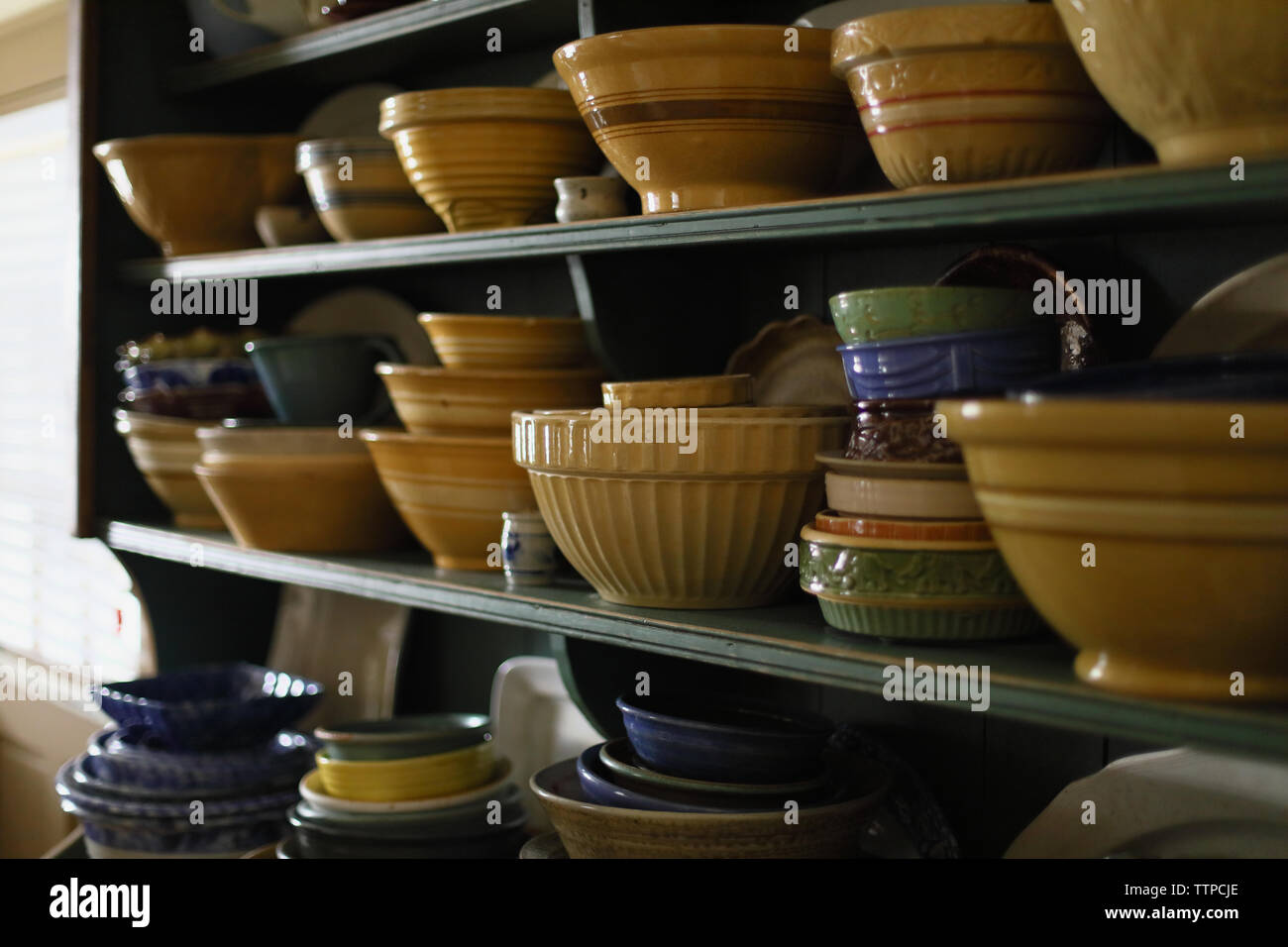 Various bowls arranged on shelves in kitchen Stock Photo