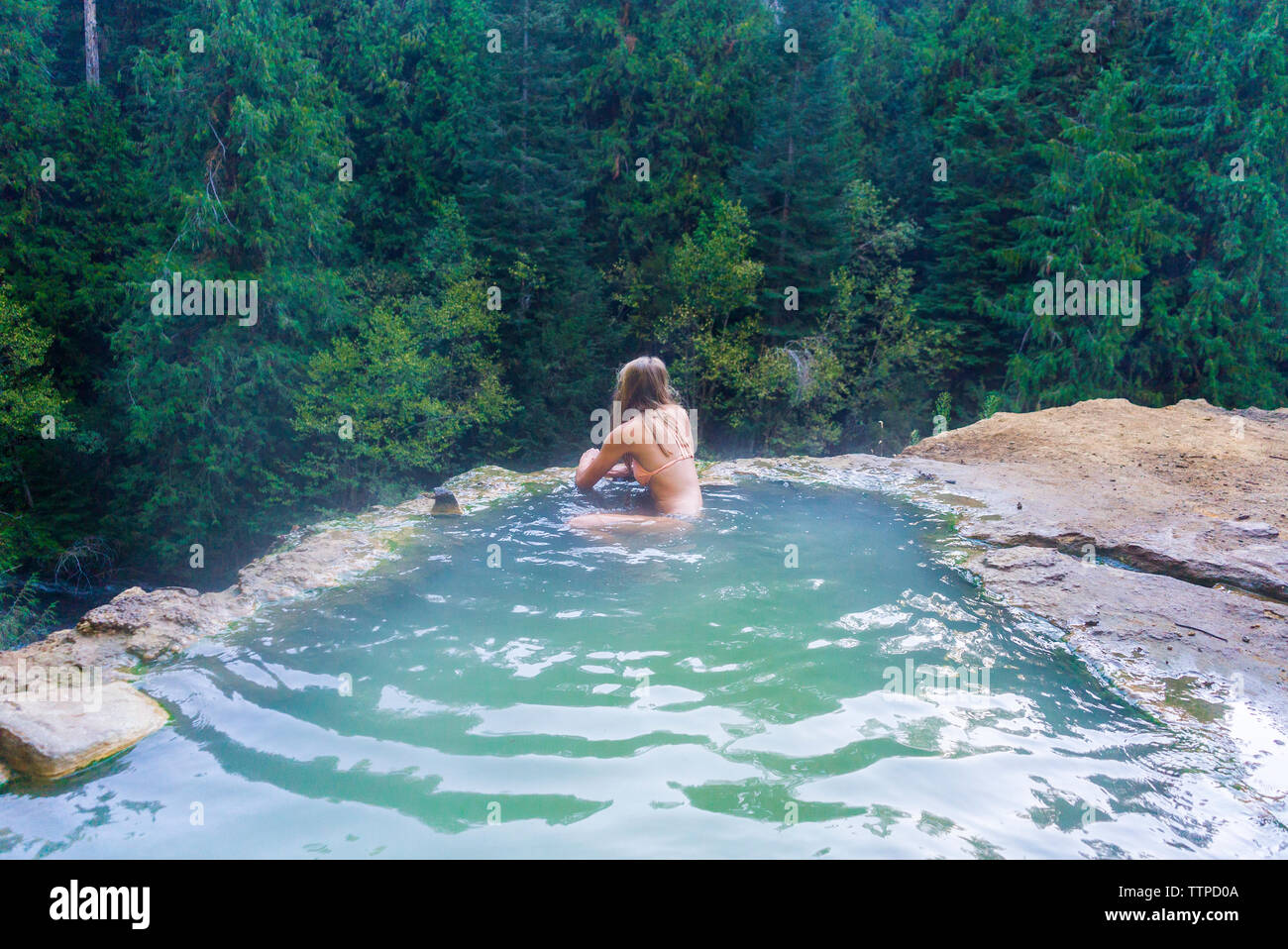 Woman swimming in hot spring at forest Stock Photo