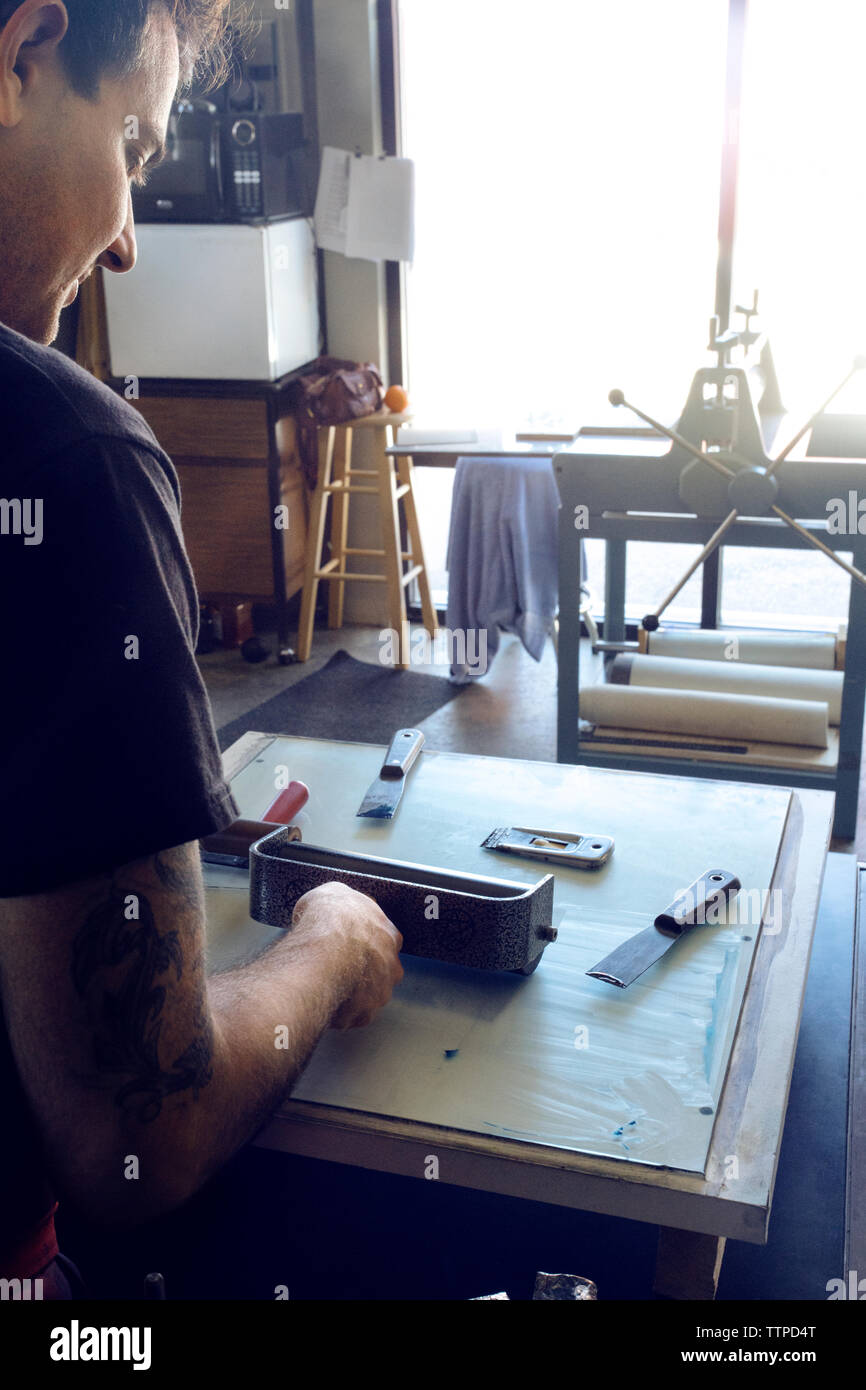 Cropped image of male lithograph worker using paint roller at workshop Stock Photo