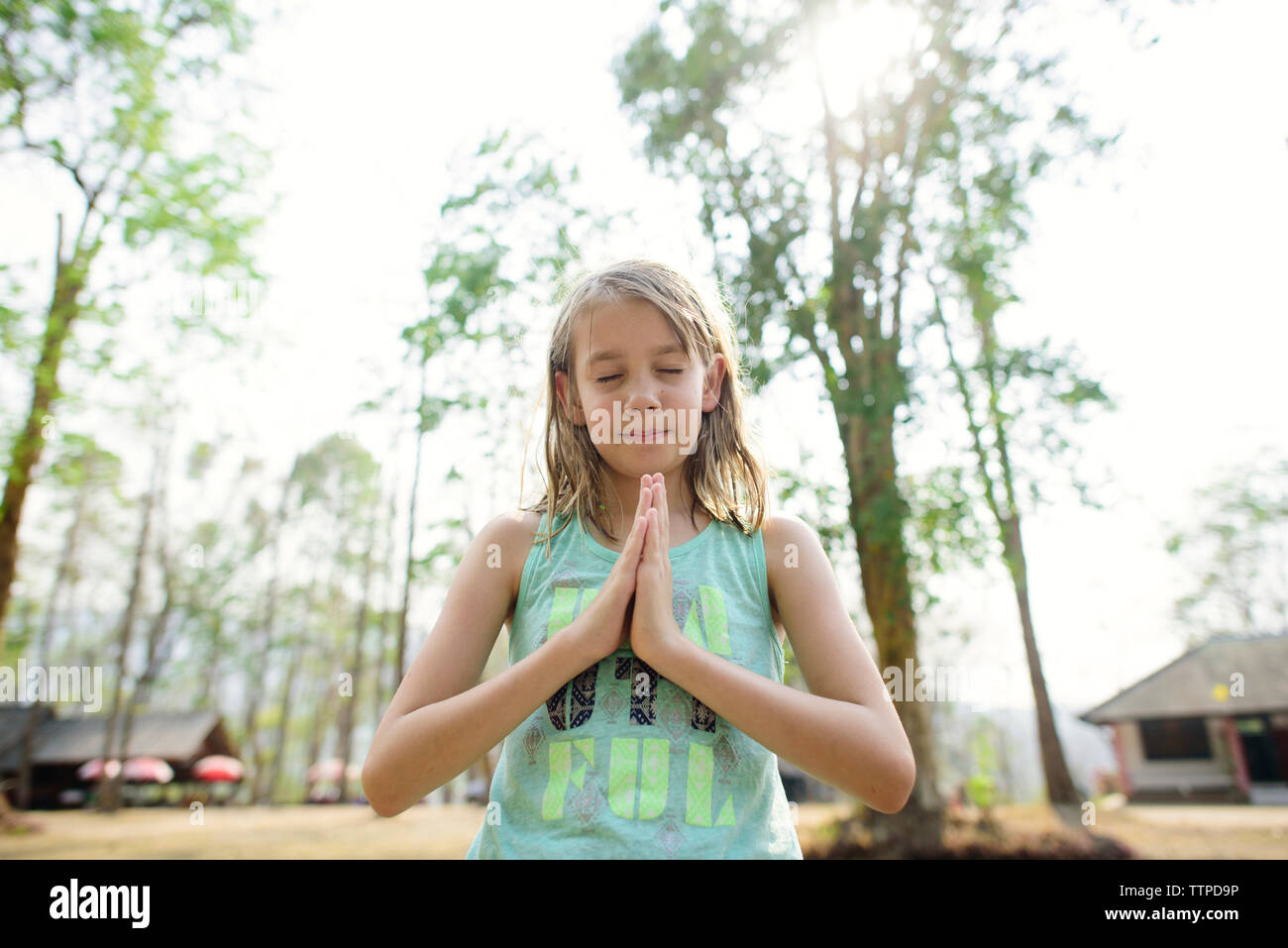 Girl with hands clasped standing against sky Stock Photo