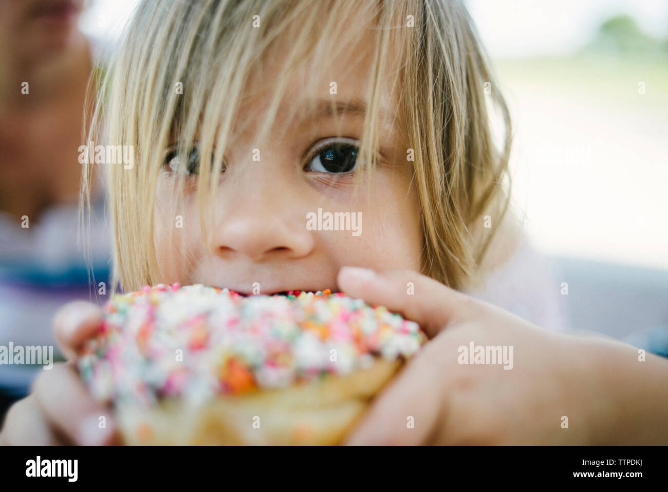 Portrait of cute girl eating donut outdoors Stock Photo