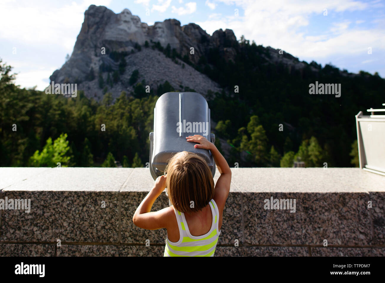 Rear view of girl looking through telescope at Mount Rushmore National Memorial Stock Photo