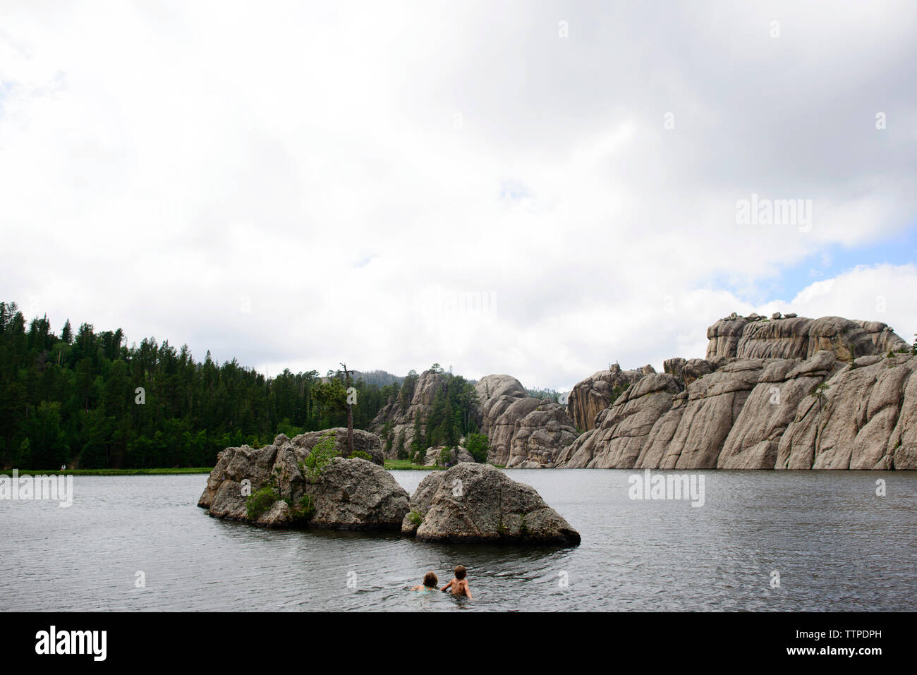Siblings swimming in Sylvan Lake against sky Stock Photo