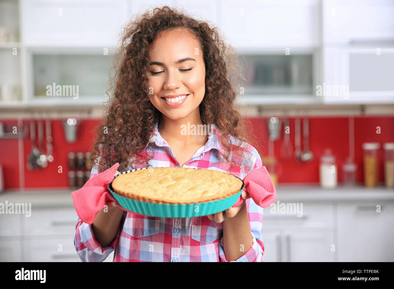 Beautiful African girl with cake in kitchen Stock Photo - Alamy