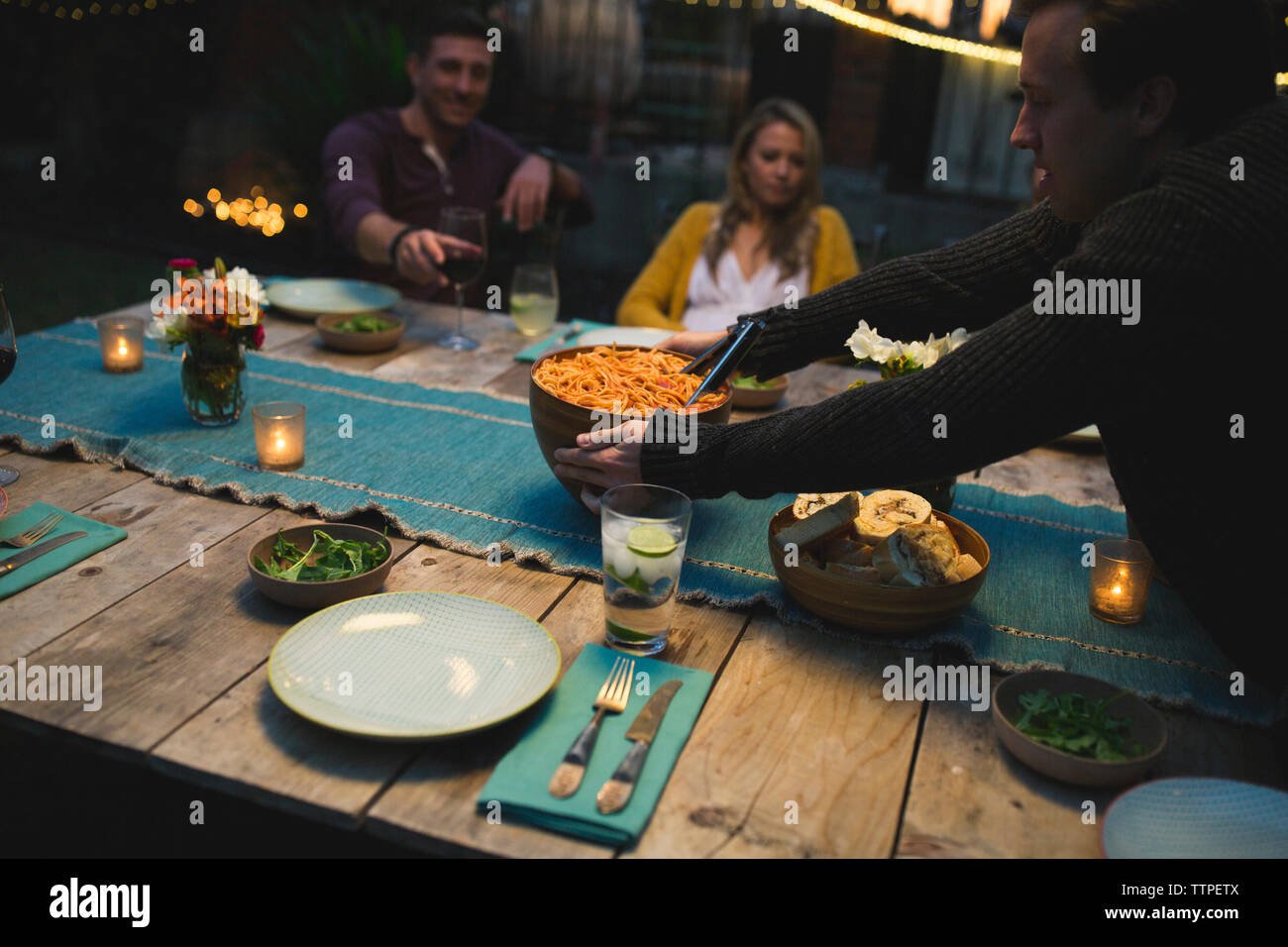 Man keeping bowl on table while during dinner with friends at patio Stock Photo
