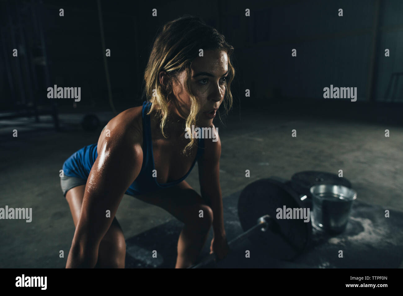 Confident female athlete lifting barbell in gym Stock Photo