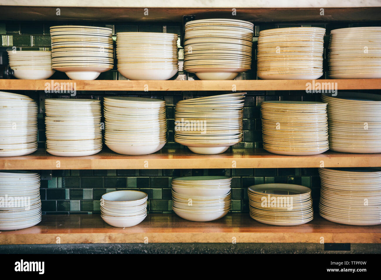 Close-up of plates and bowls on shelves at commercial kitchen Stock Photo