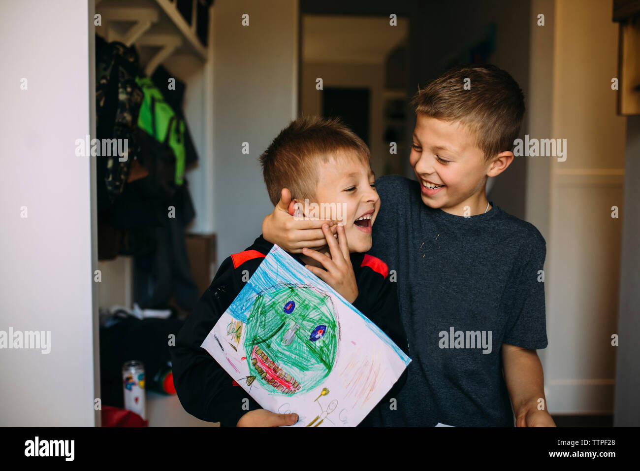 Cheerful boy holding brother's face while playing at home Stock Photo