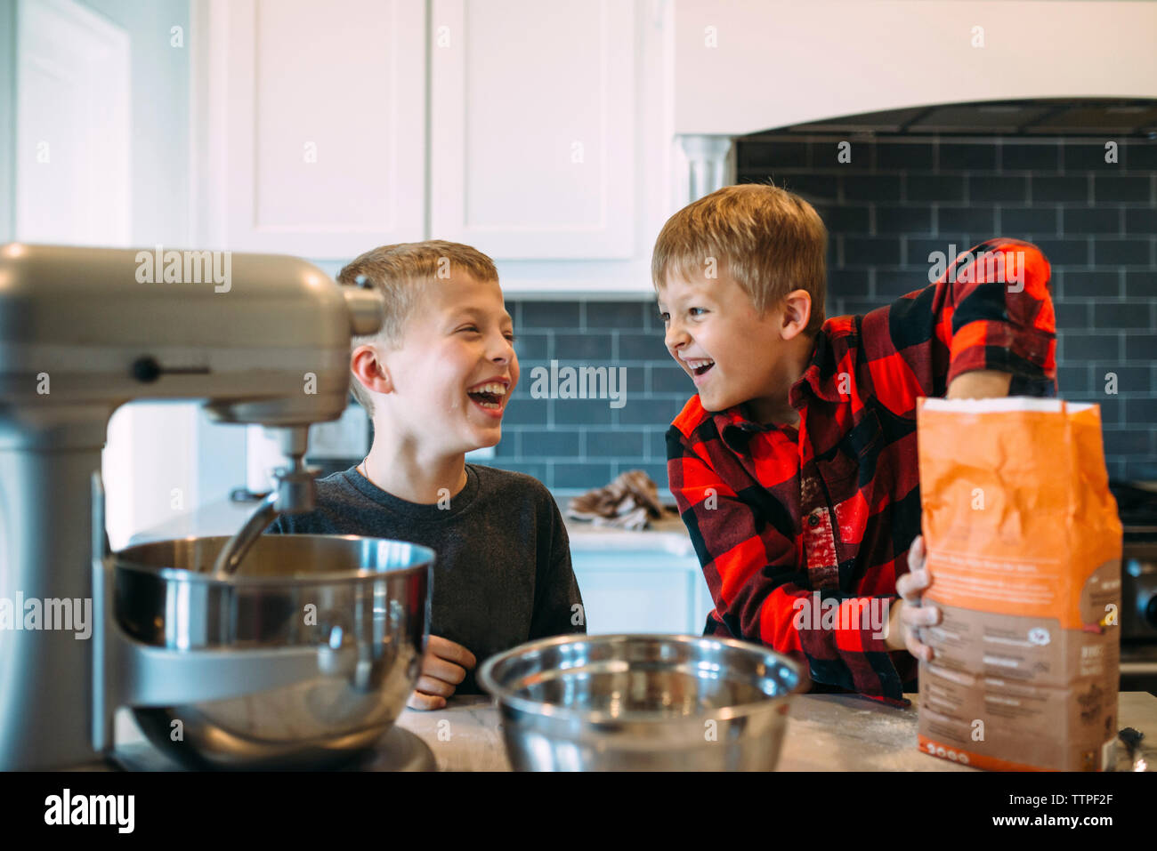 Happy brothers preparing food in kitchen at home Stock Photo