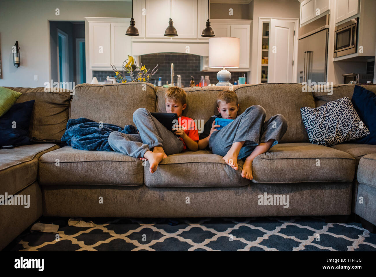 Brothers using tablet computers while relaxing on sofa at home Stock Photo