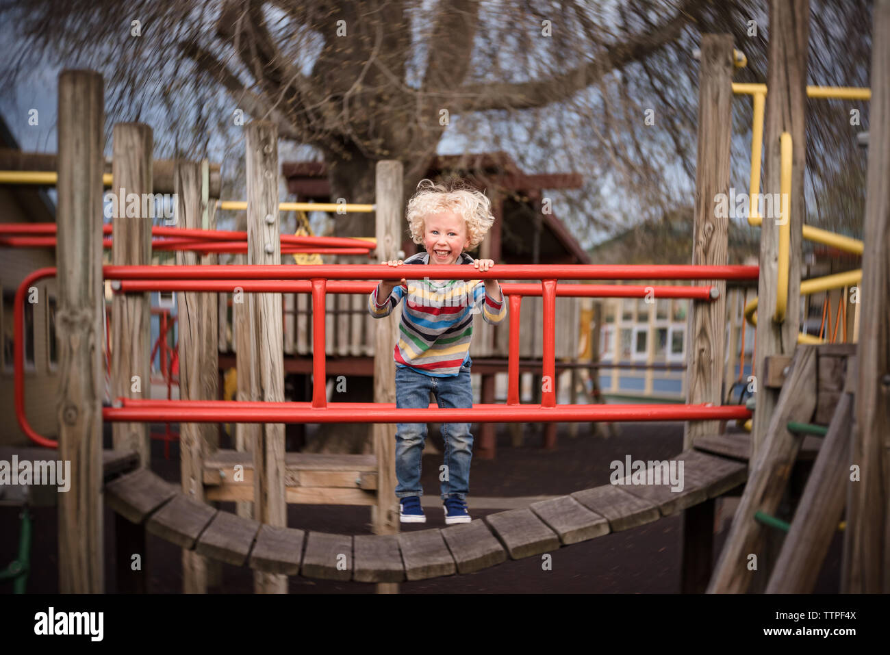 Happy active toddler jumping on colorful playground structure Stock Photo