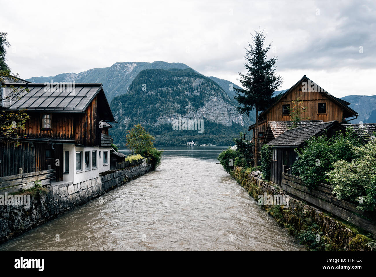 Lake flowing amidst houses against mountains in village Stock Photo Alamy