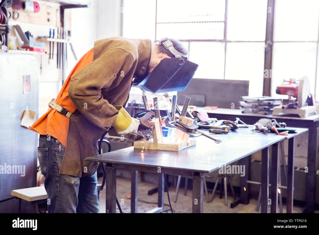 Male craftsperson welding metal at wood shop Stock Photo