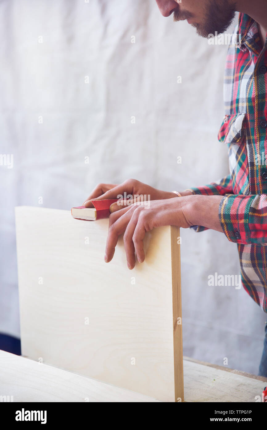 Cropped image of craftsman sanding wooden plank at workshop Stock Photo