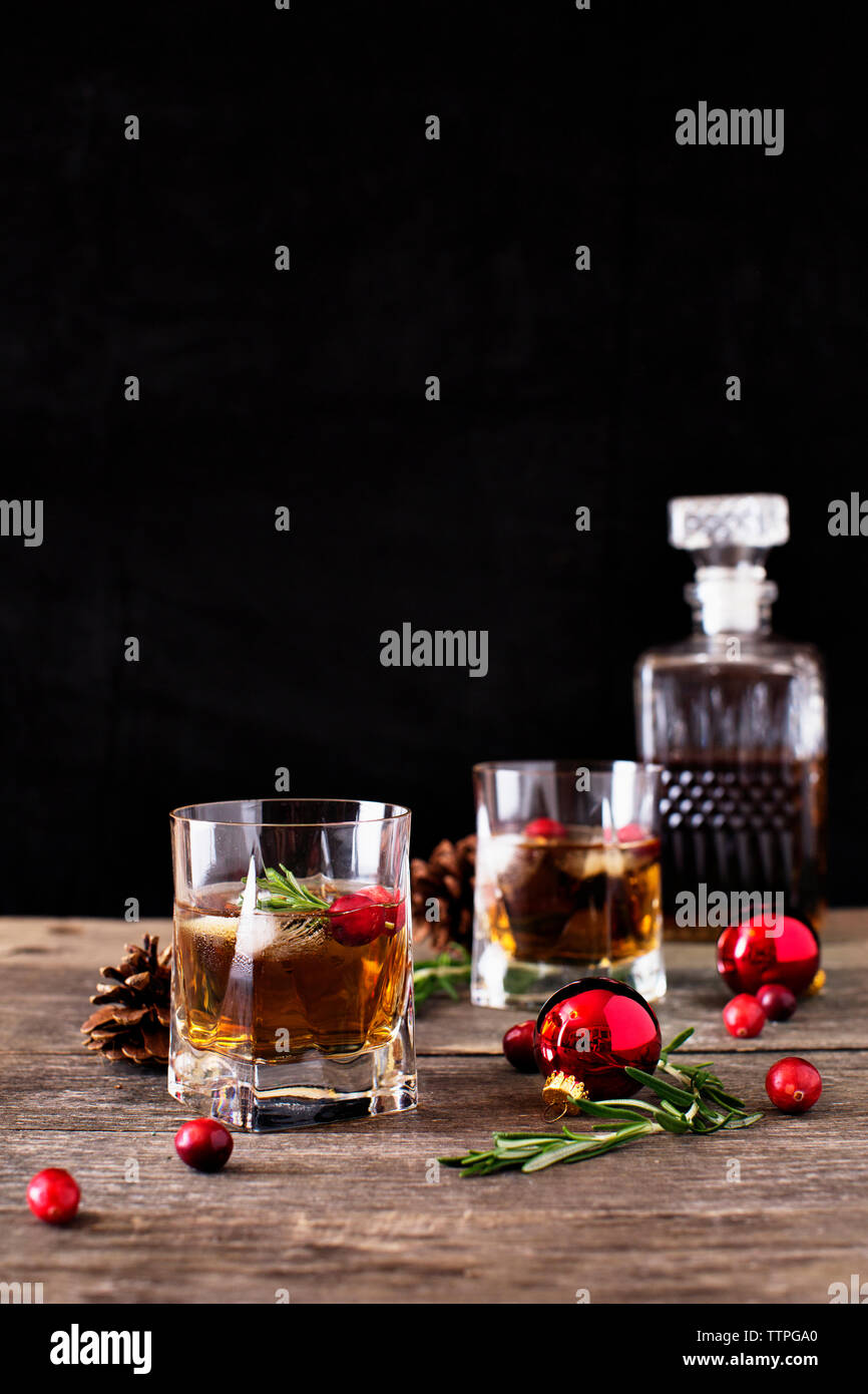 Close-up of drinks with baubles and cranberries on wooden table against black background Stock Photo