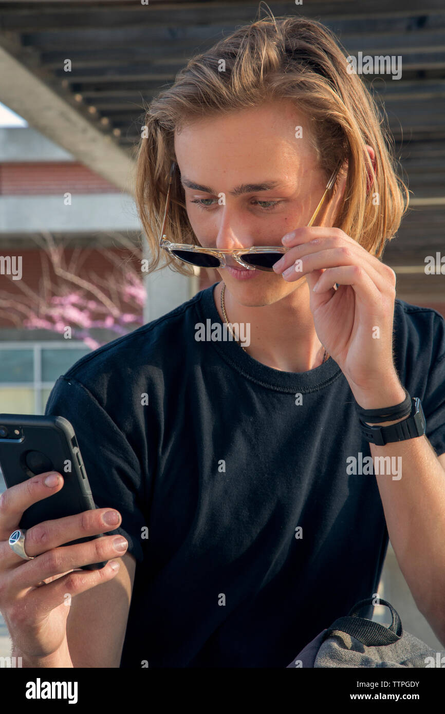 Close up of male student looking at phone over sunglasses Stock Photo