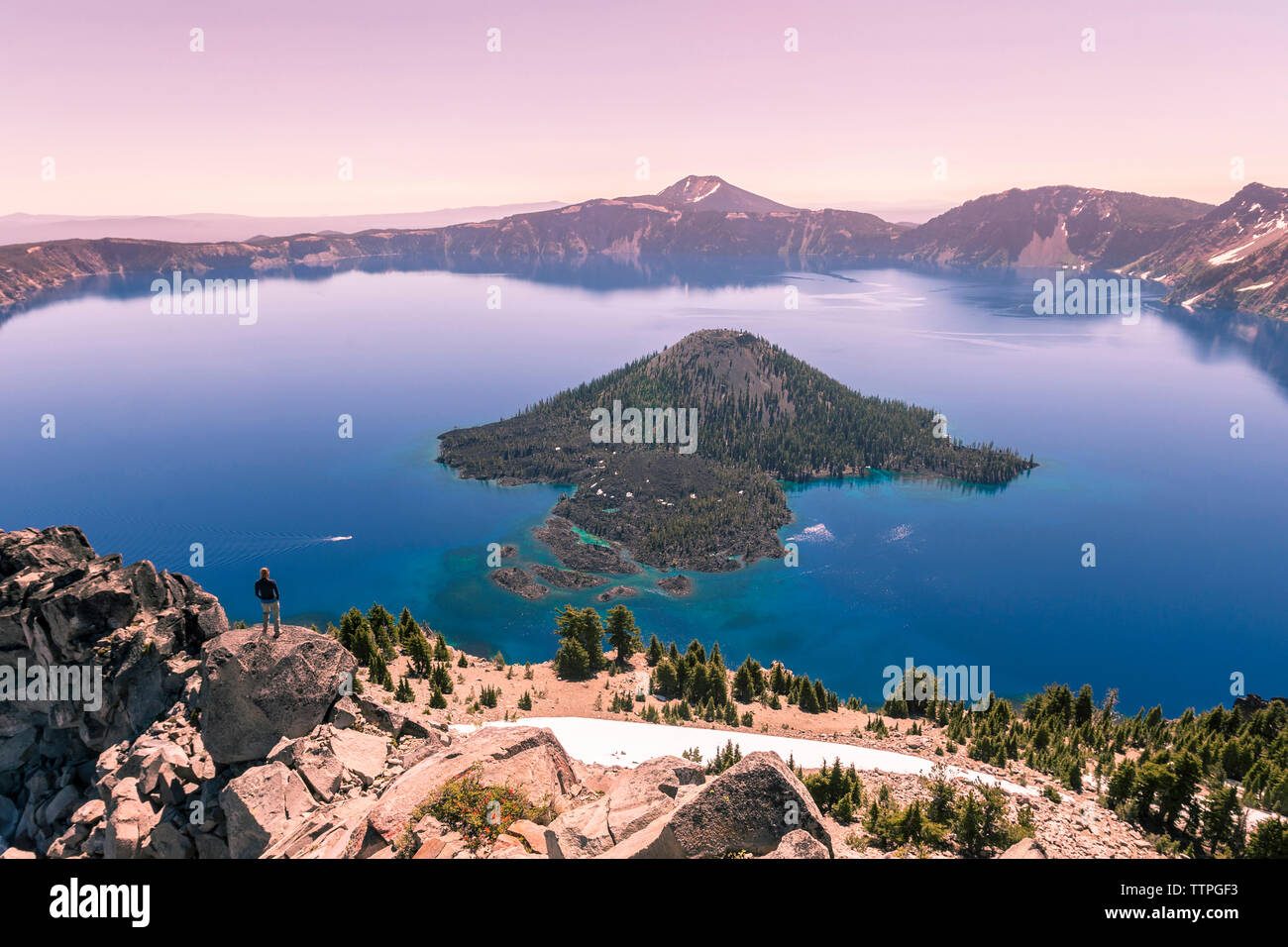 Woman looking at view while standing on rock against clear sky Stock Photo