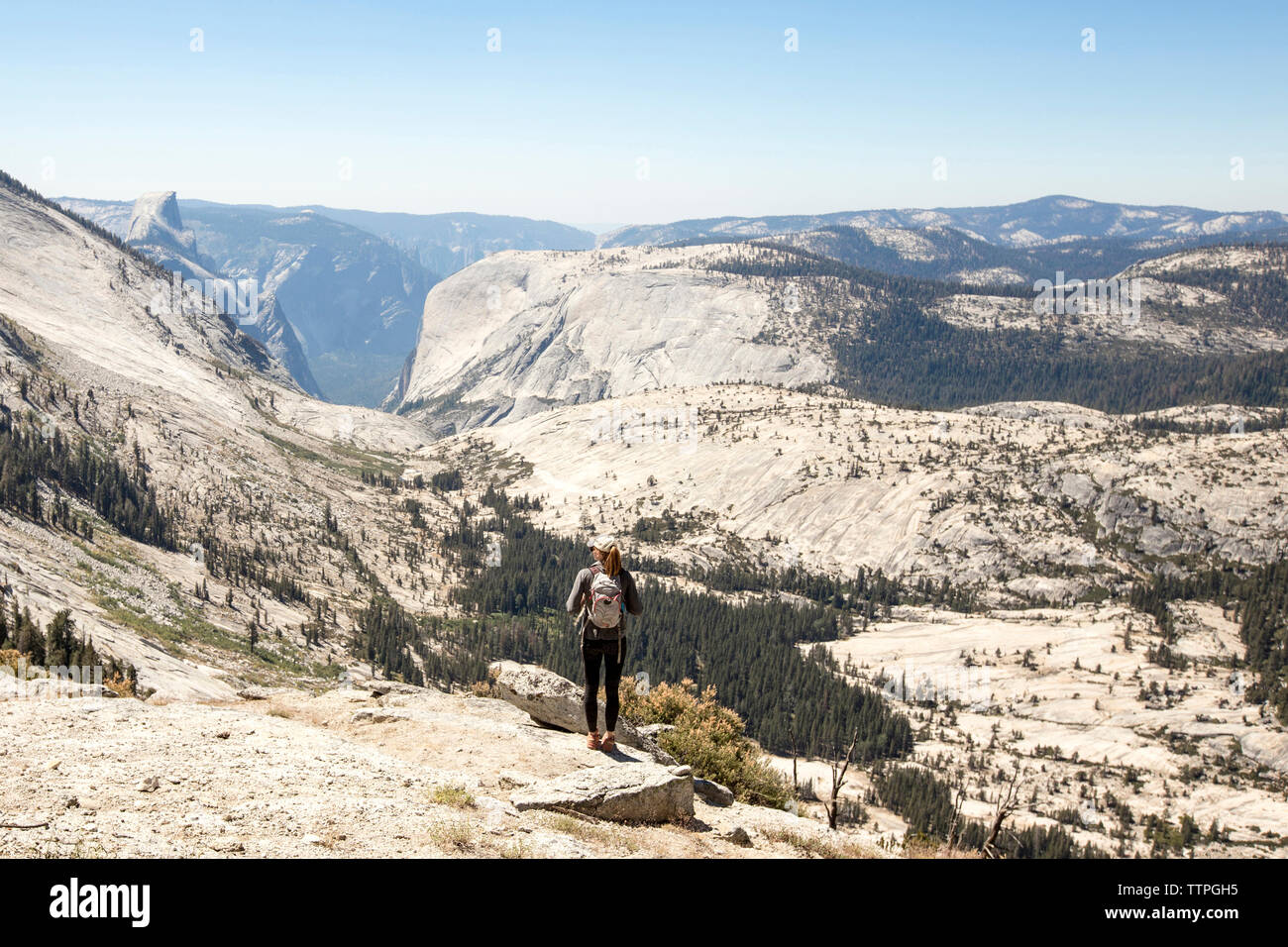 Rear view of hiker standing on mountain on sunny day Stock Photo - Alamy