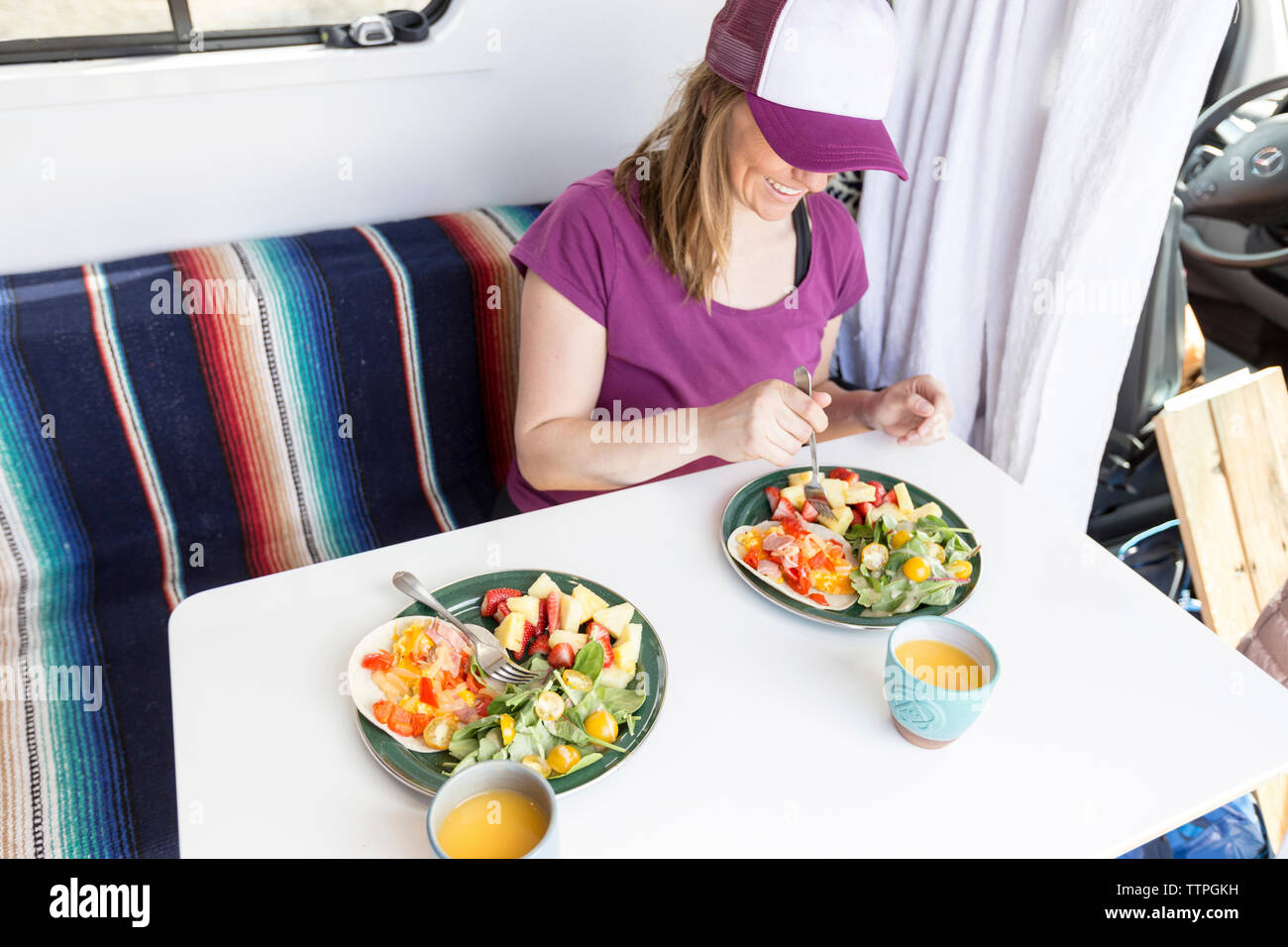 High angle view of happy woman having food while sitting in travel trailer Stock Photo