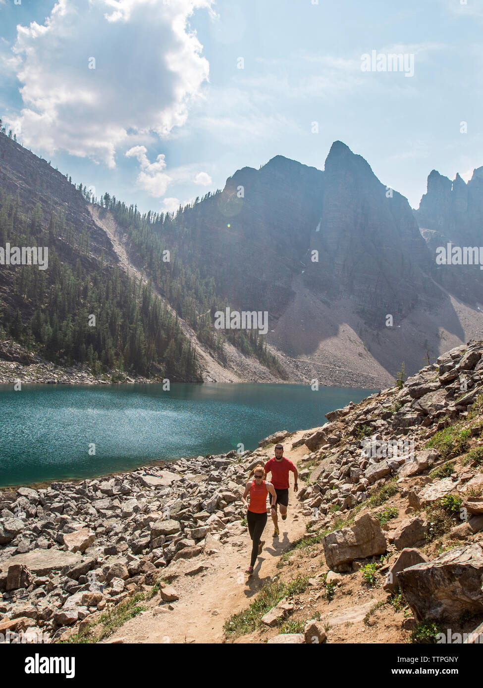 High angle view of friends running by river against mountains at Banff National Park during sunny day Stock Photo