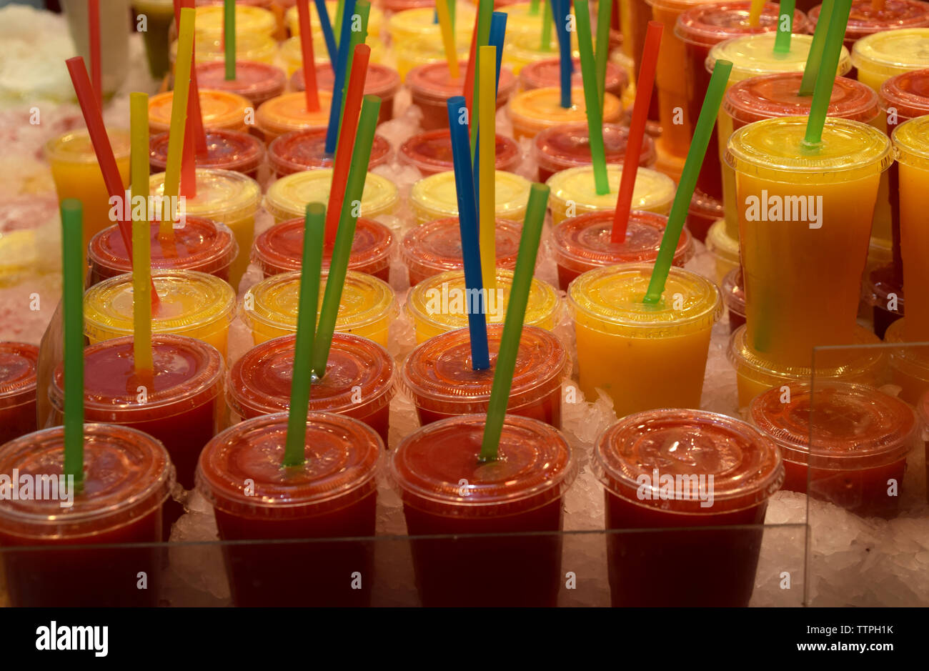 Freshly squeezed juice in plastic mugs with plastic straws in different