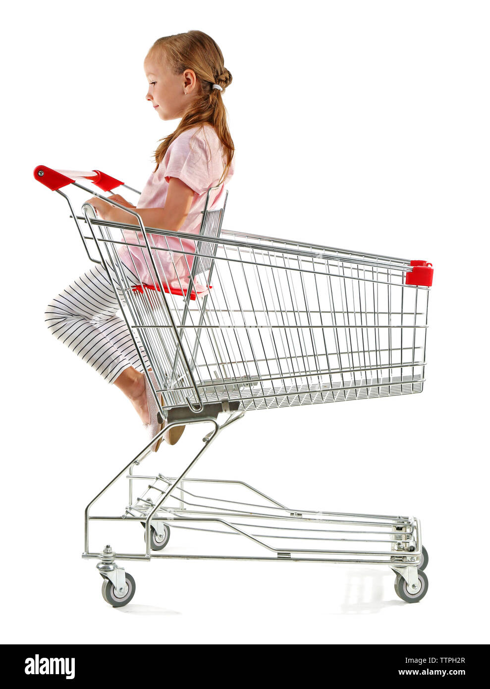 Cute girl sitting in shopping cart on white background Stock Photo - Alamy