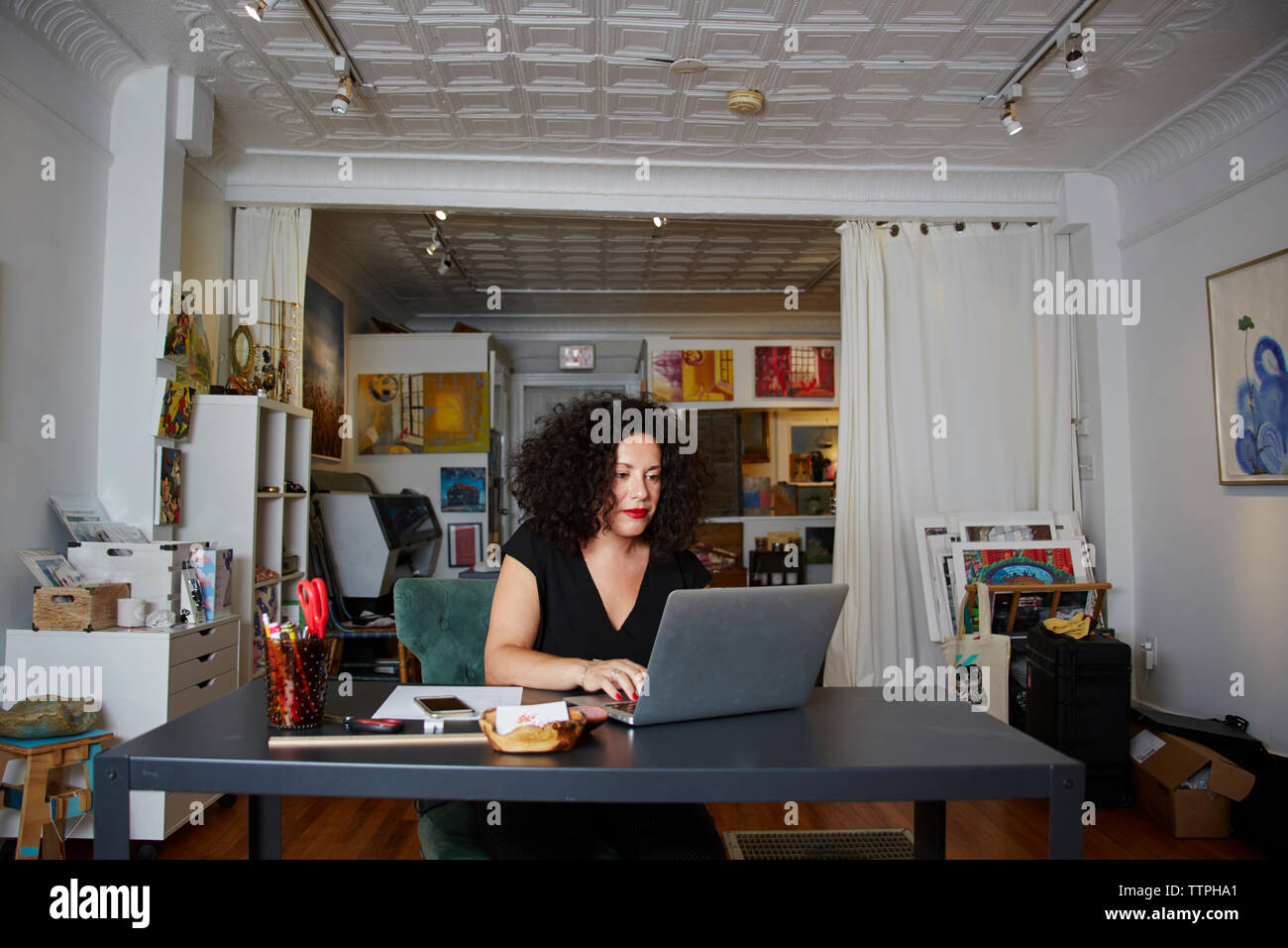 Female owner using laptop computer at table in gallery Stock Photo