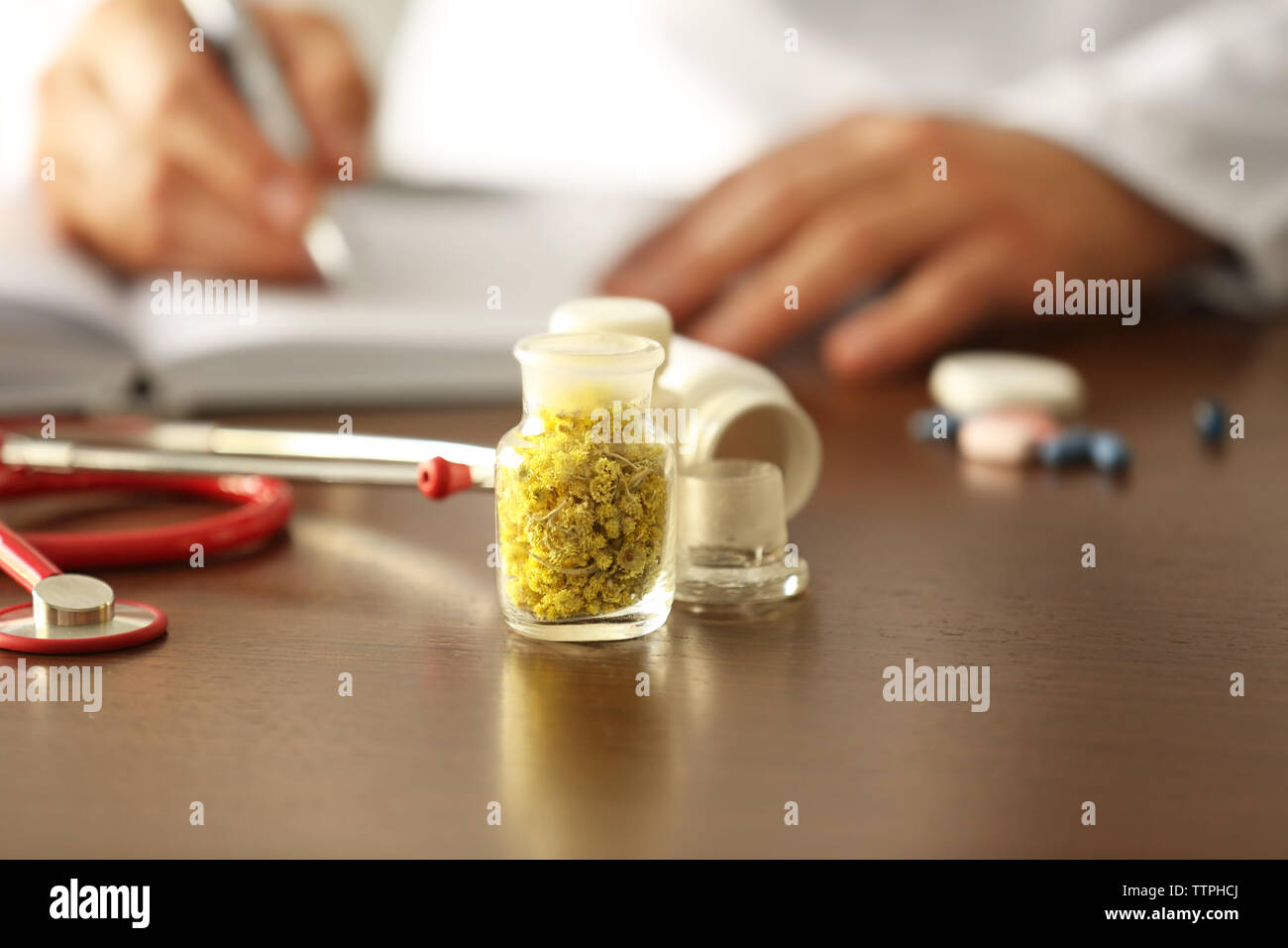 Bottle with dry inflorescence and doctor on background. Herbal medicine concept Stock Photo