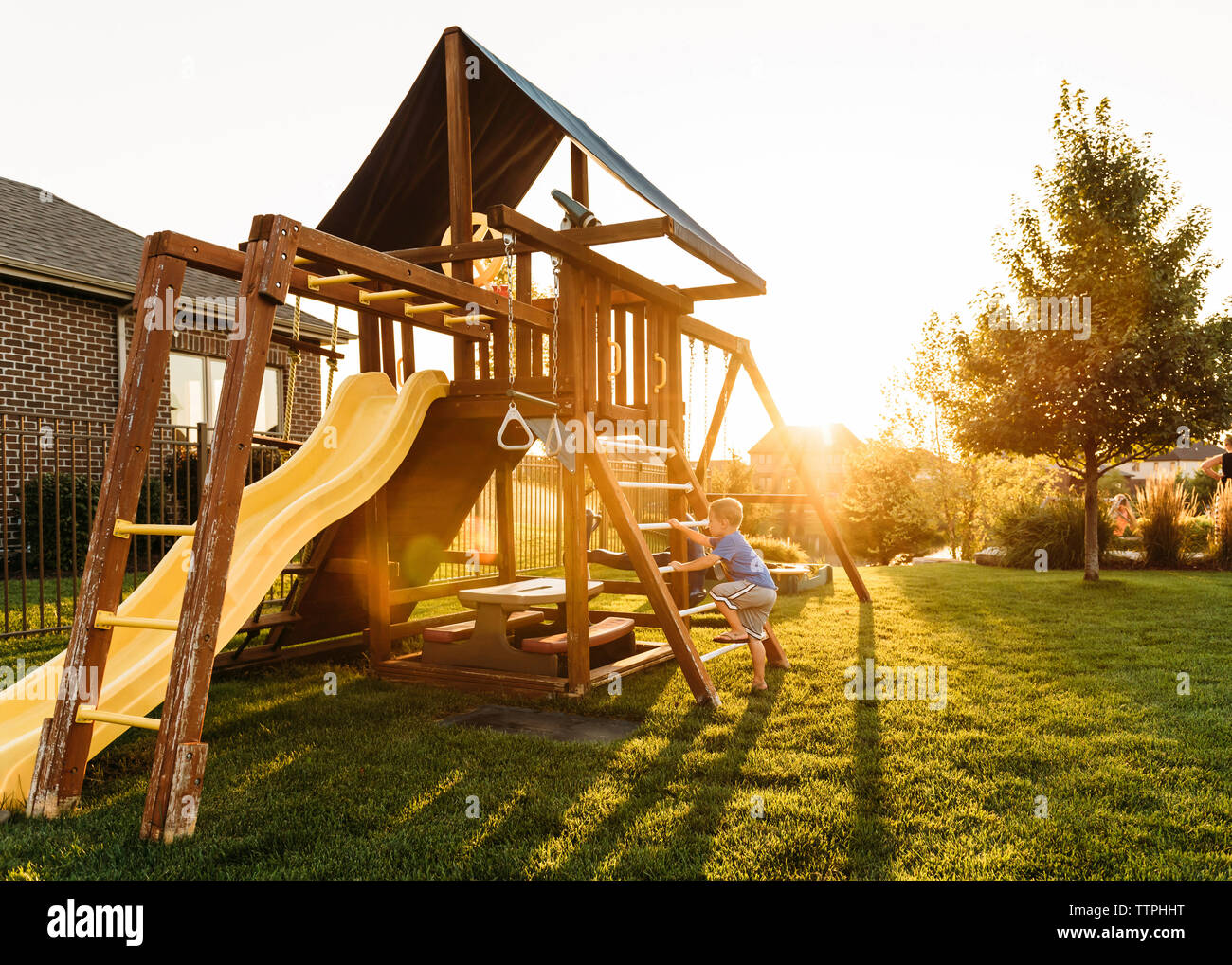 Boy playing in backyard during sunset Stock Photo