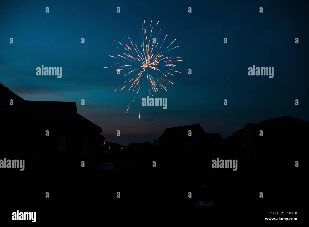 Low angle view of firework display over silhouette houses against sky at night Stock Photo