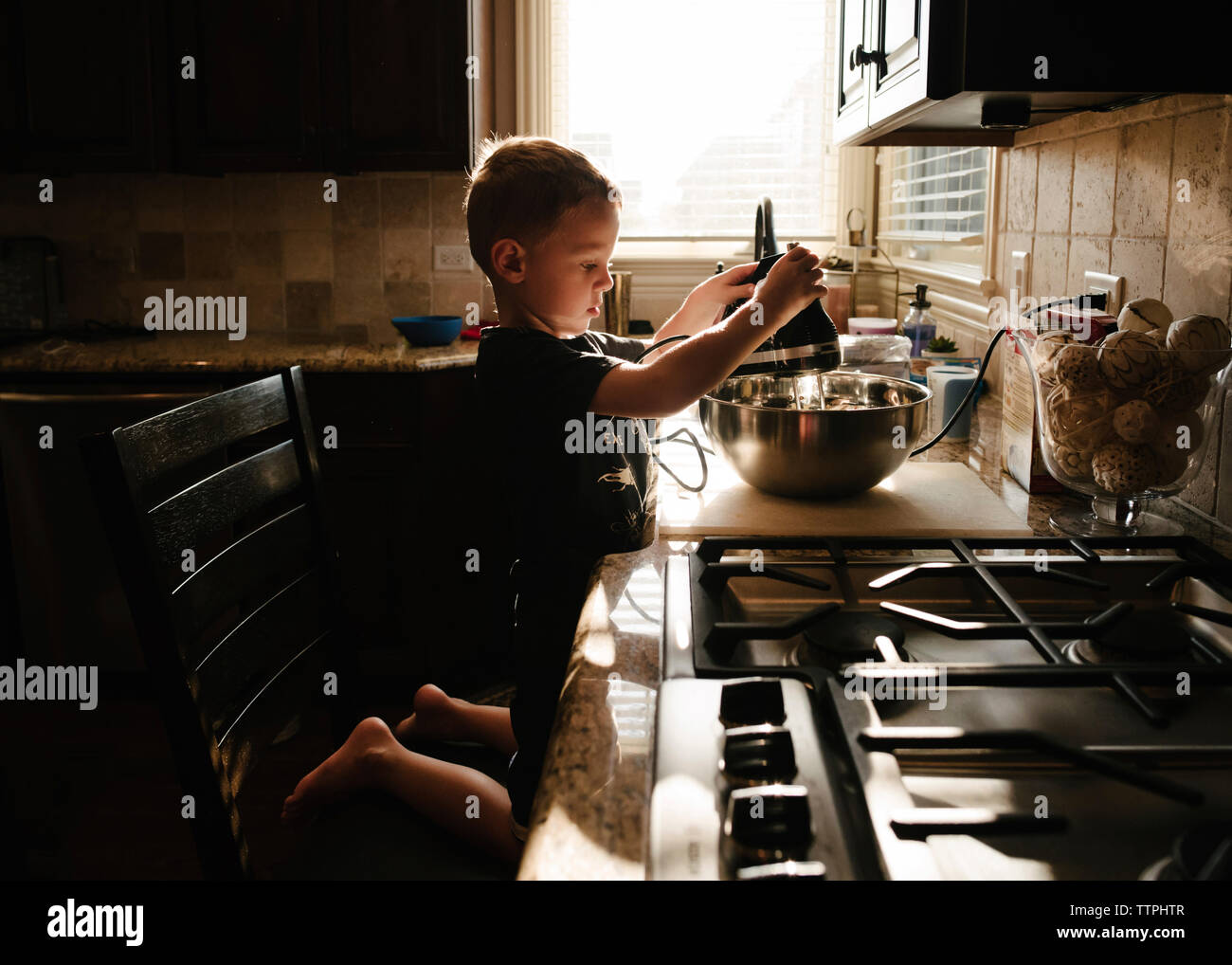 Side view of boy preparing food in kitchen at home Stock Photo