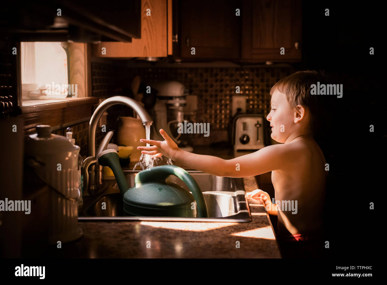 A Young Boy Curious With Water From The Kitchen Sink Stock Photo Alamy
