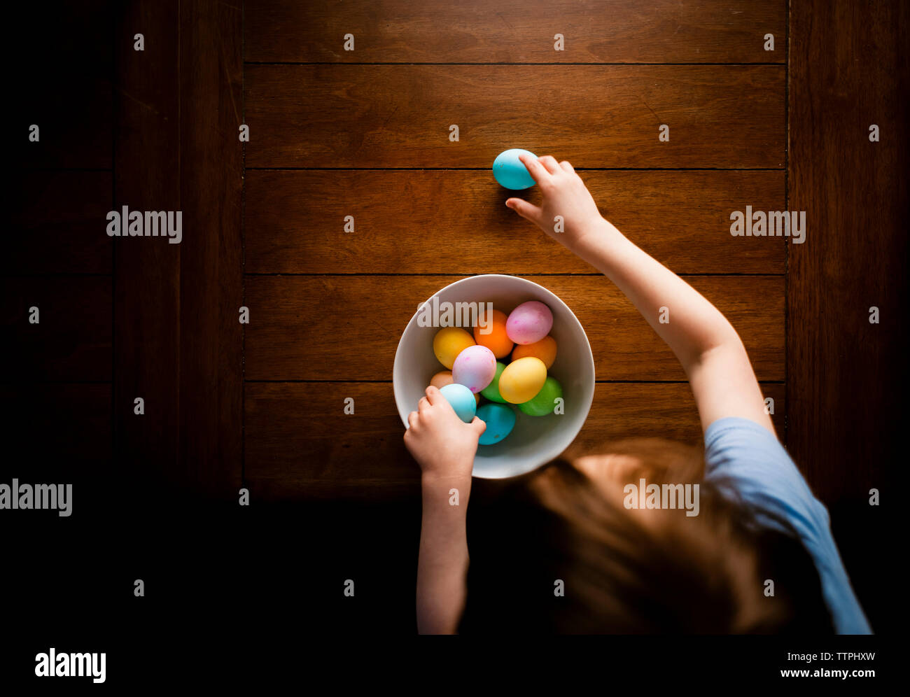 Above Perspective Of A Young Boy Gathering Easter Eggs From Table Stock Photo