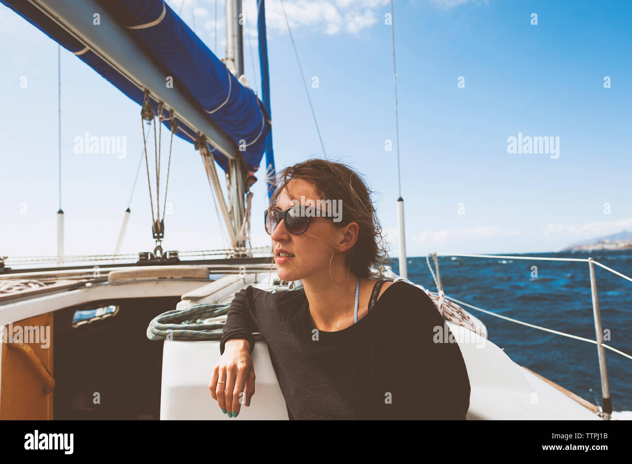 Young woman travelling in sailboat on sea against sky Stock Photo