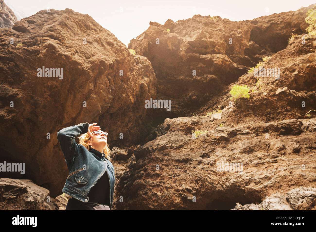Mature woman looking up while standing against rocks Stock Photo