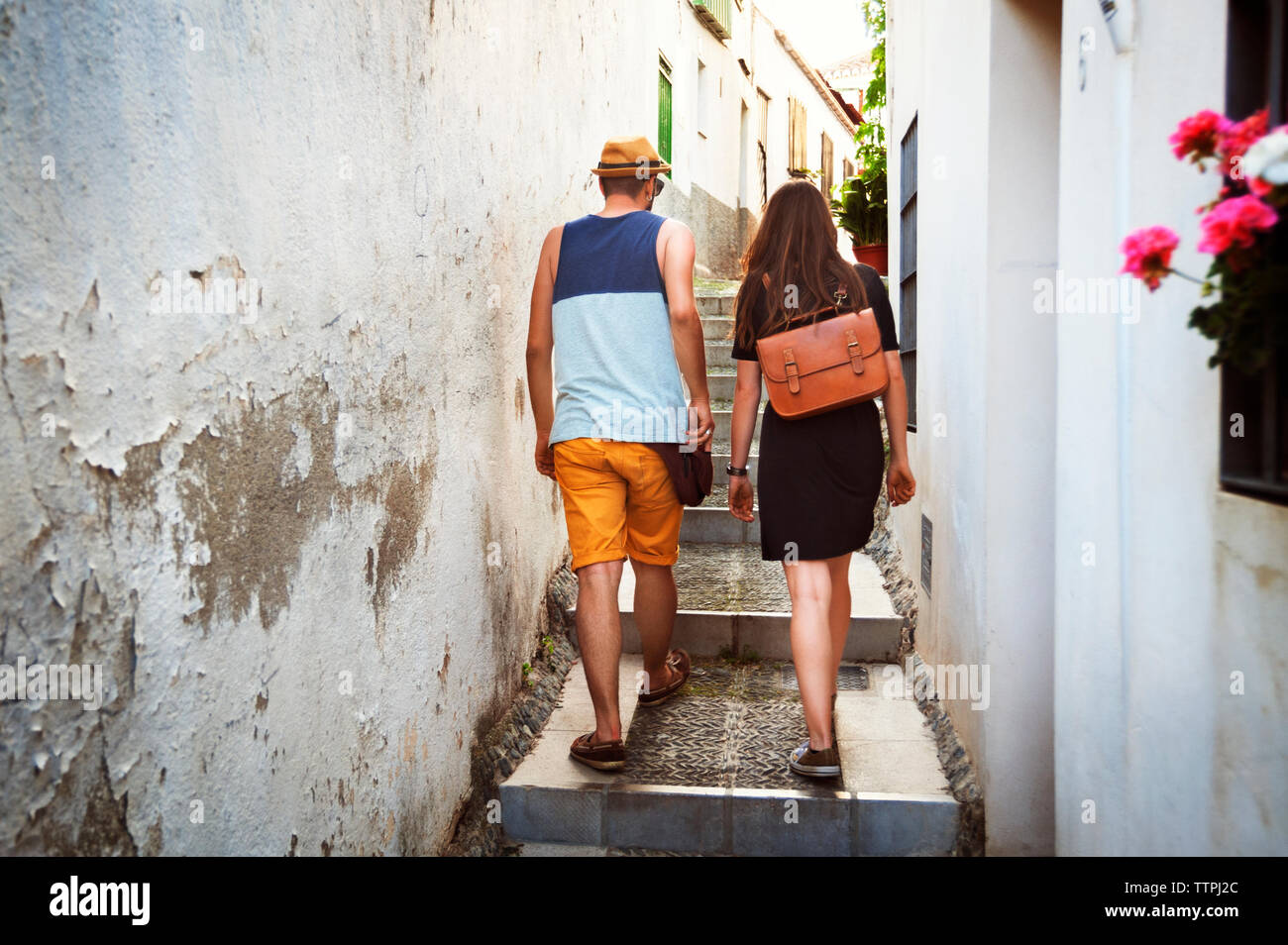 Rear view of couple climbing staircase amidst buildings Stock Photo