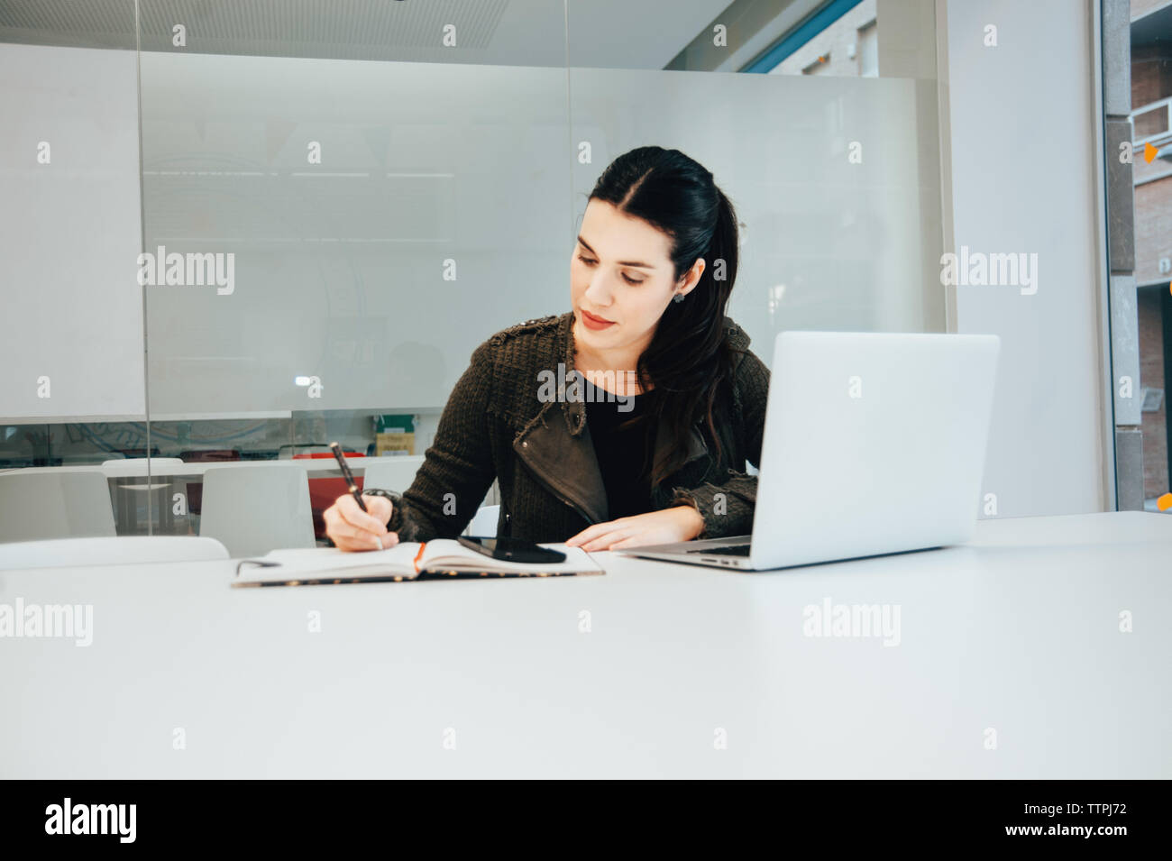 Young Hispanic Woman Working on Laptop in Classroom Stock Photo