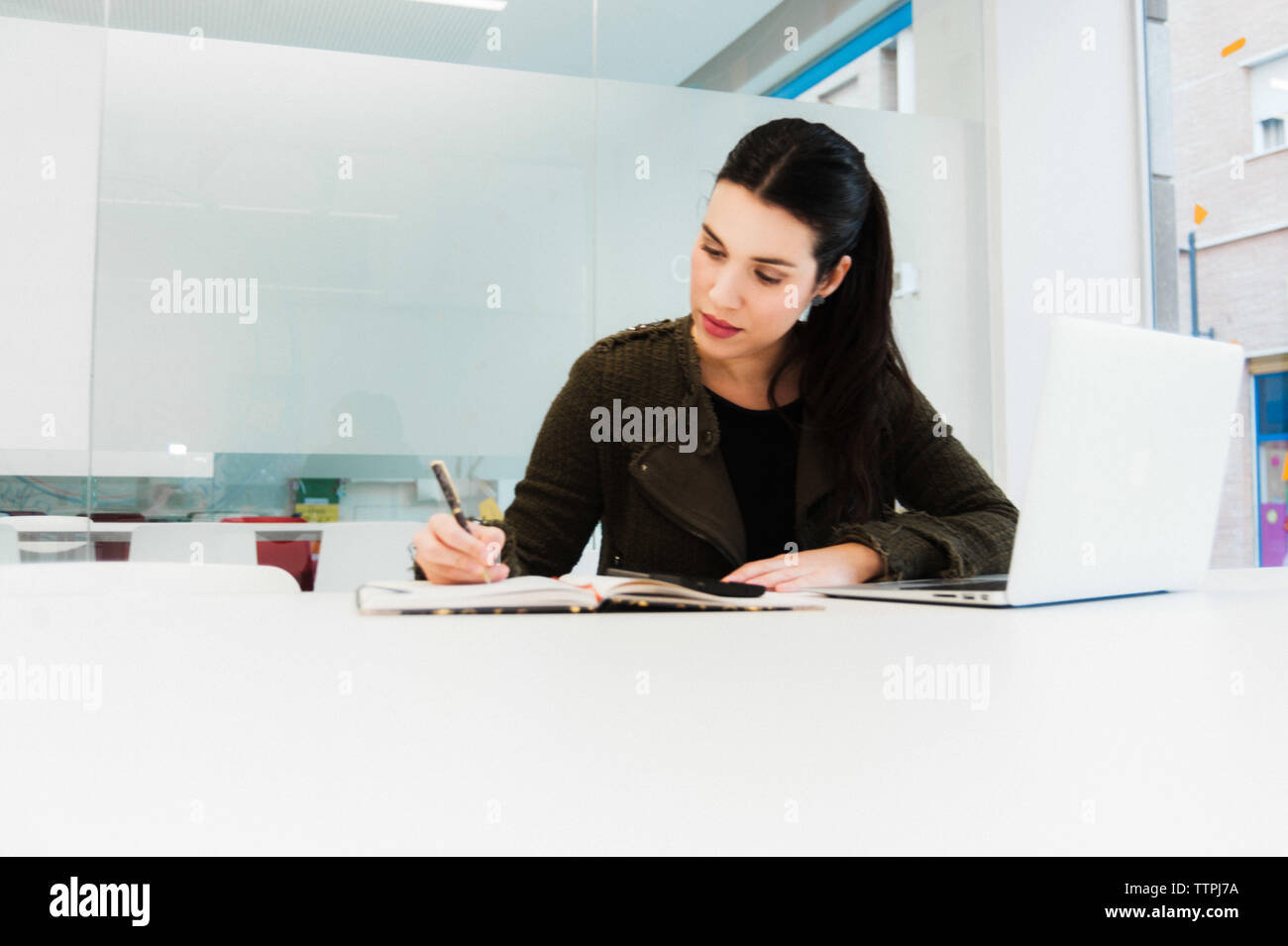 Young Hispanic Woman Working on Laptop in Classroom Stock Photo