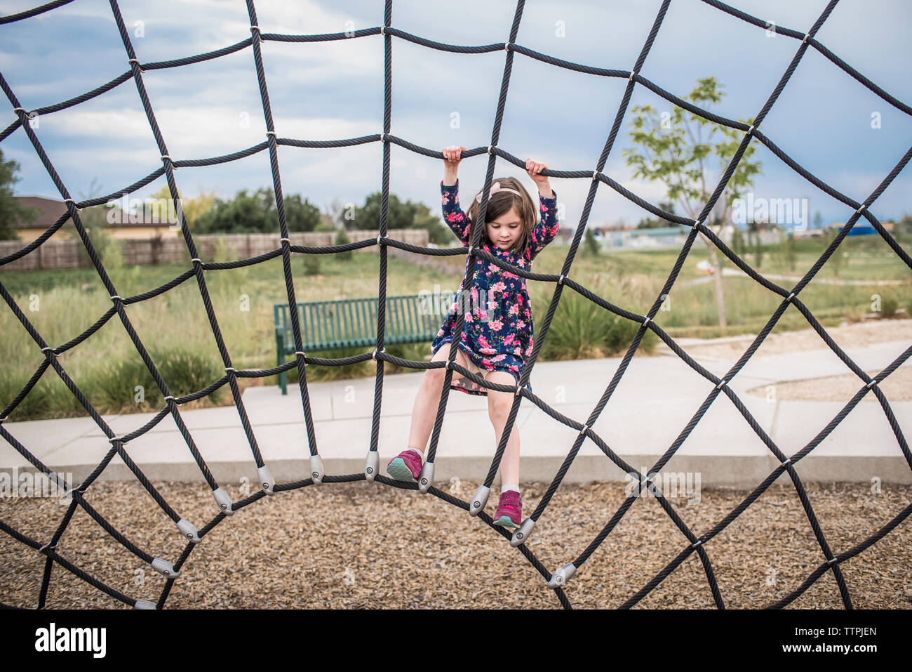Carefree girl playing on rope at playground Stock Photo