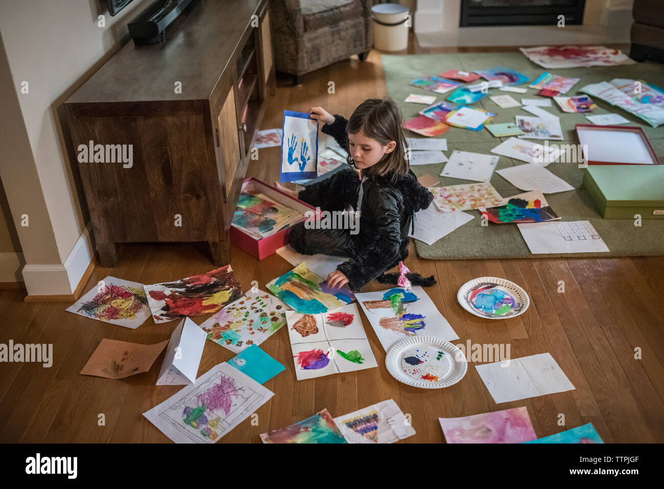 High angle view of girl painting on papers while sitting on floor at home Stock Photo